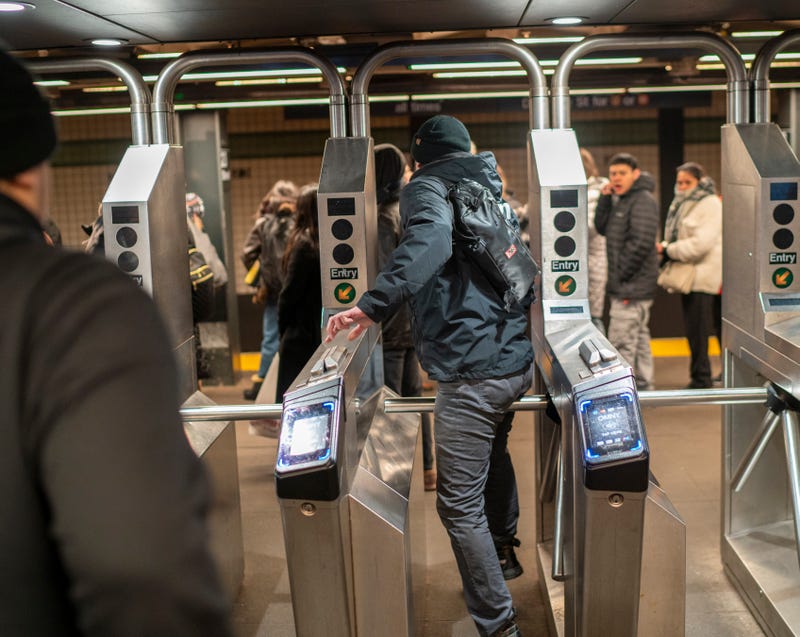 A man jumps a turnstile during rush hour in the subway