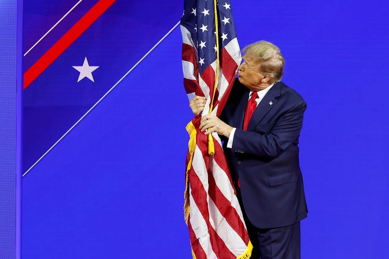 NATIONAL HARBOR, MARYLAND - FEBRUARY 24: Republican presidential candidate and former U.S. President Donald Trump hugs an American flag as he arrives at the Conservative Political Action Conference (CPAC) at the Gaylord National Resort Hotel And Convention Center on February 24, 2024 in National Harbor, Maryland. Attendees descended upon the hotel outside of Washington DC to participate in the four-day annual conference and hear from conservative speakers from around the world who range from journalists, U.S. lawmakers, international leaders and businessmen. (Photo by Anna Moneymaker/Getty Images)