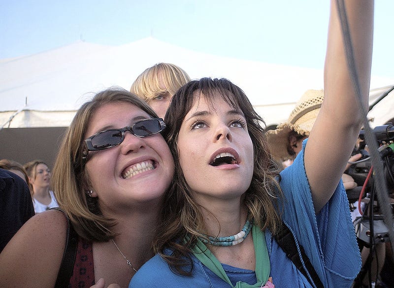 Parker Posey takes a picture of herself with a fan.