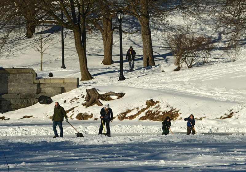 A family is seen shoveling snow to reveal the ice on the Washington Park Lake in Albany, N.Y