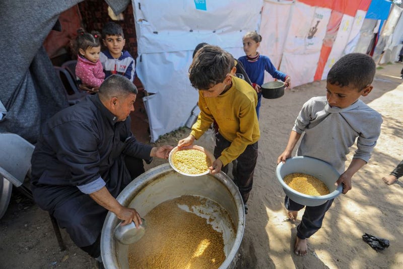 Citizens queue for food that is cooked in large pots and distributed for free during war-time on March 10, 2024 in Rafah, Gaza.