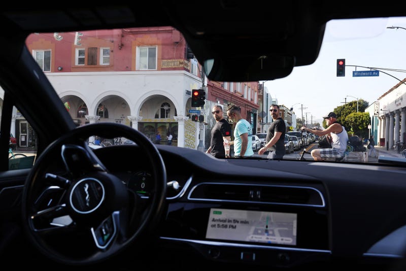 Pedestrians look toward a Waymo autonomous self-driving Jaguar taxi stopped at a red light near Venice Beach on March 14, 2024 in Los Angeles, California. Beginning today, Waymo One is offering robotaxi services in a 63-square mile area of greater Los Angeles including Santa Monica, Venice and downtown with over 50,000 people on the wait list. Waymo is owned by Alphabet, Google’s parent company. 