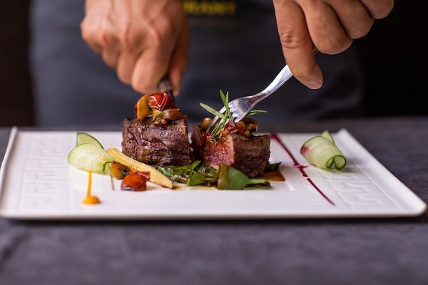 Man cutting a piece of steak with vegetables