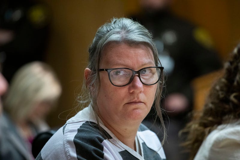 Woman in prison garb looking straight toward camera