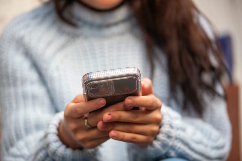 A young woman holds a smartphone in her hands