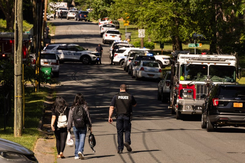A Charlotte-Mecklenburg Police Department officer, right, escorts two young girls who were trying to get home after school near the scene of a shootout on the 5000 block of Galway Drive in east Charlotte, North Carolina, on Monday, April, 29, 2024.