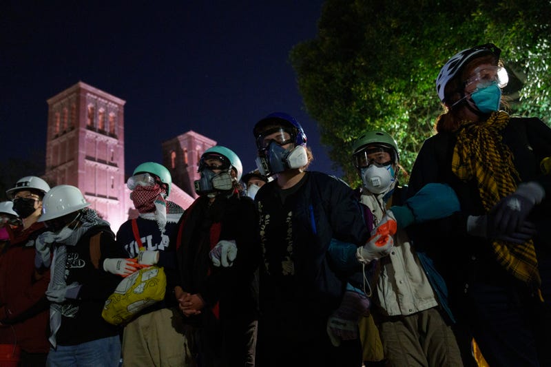 Pro-Palestine Protestors link arms across from members of law enforcement in an encampment at UCLA on May 2, 2024 in Los Angeles, California.