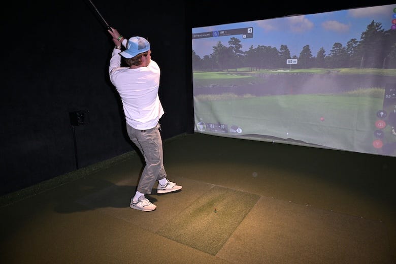 Man hitting a shot at a golf simulator