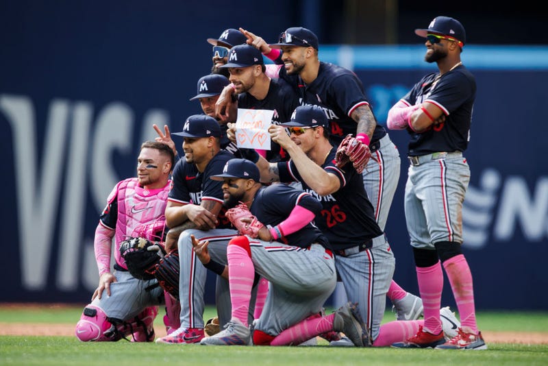 Max Kepler #26 of the Minnesota Twins holds up a '<3 Mom' sign as the team takes a celebratory team photo after their MLB game win against the Toronto Blue Jays at Rogers Centre on May 12, 2024 in Toronto, Canada. 