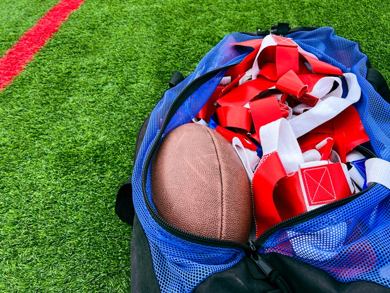 A large athletic duffel bag is filled with equipment for flag football play.