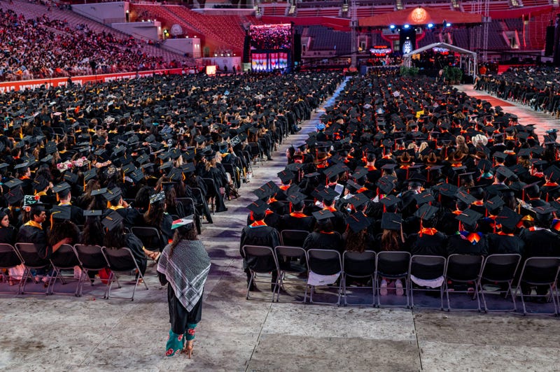 A graduate student wearing a Palestinian-decorated graduation cap walks down the aisle during commencement at the DKR-Texas Memorial Stadium on May 11, 2024, in Austin, Texas.