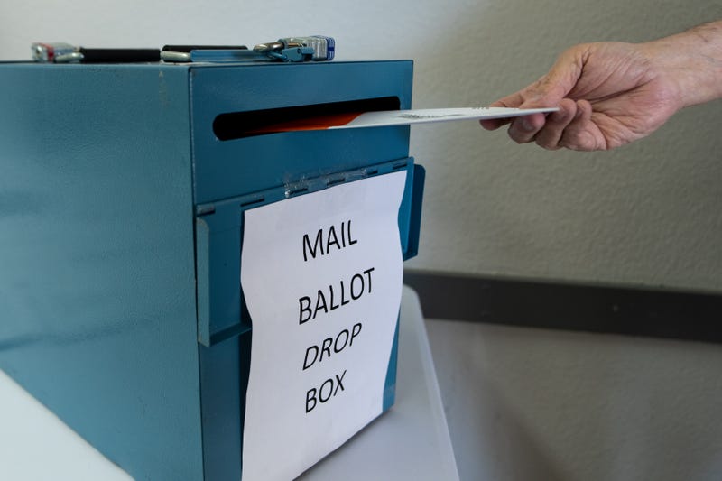 A voter deposits their mail in ballot