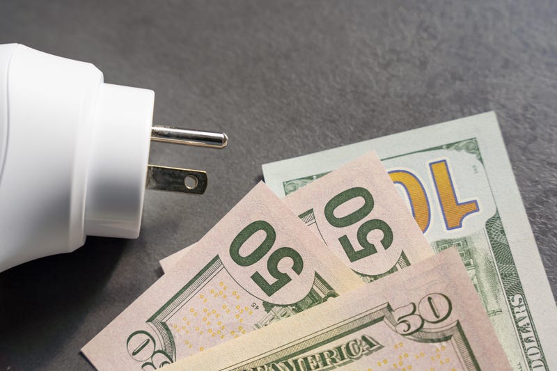 $50 and $100 bills near a wall plug.