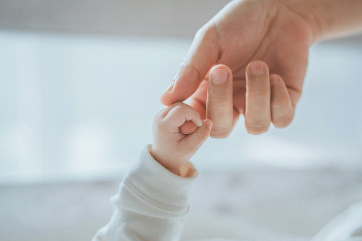 Close-up little hand of baby grasping on to mother's finger