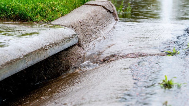 Stormwater flowing into street intake drain after a rainstorm - stock photo