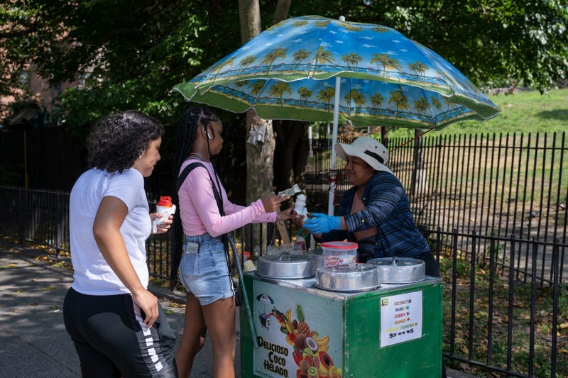 People buy ice cream from a vendor during a summer heat wave in the Bronx on July 11, 2024