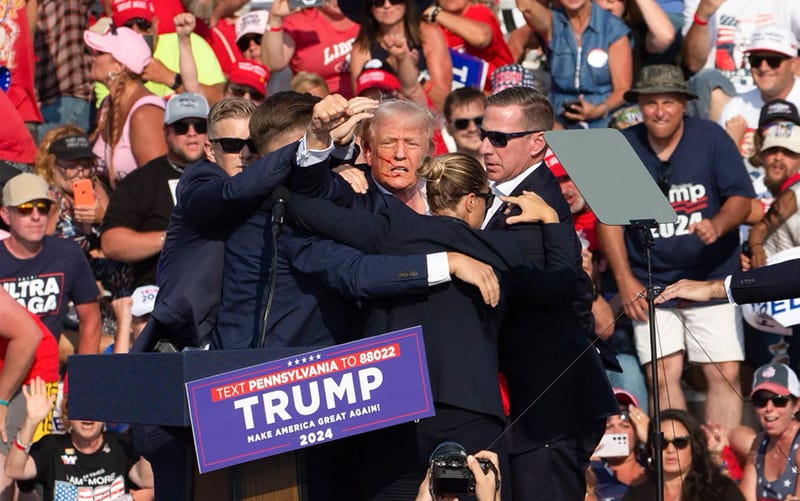 Republican presidential candidate Donald Trump is seen with blood on his face, surrounded by secret service agents, as he is taken off the stage at a campaign event in Butler, Pa., on July 13, 2024.