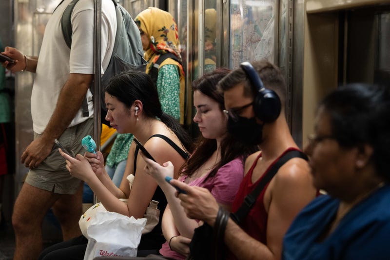 A person uses a fan to cool down on a 1 train on July 16, 2024