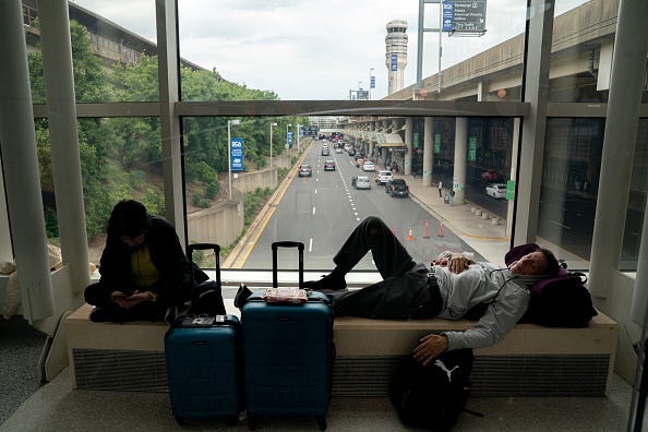  Carl Salazar (right) sleeps at Ronald Regan Washington National Airport while waiting for a delayed United flight on July 19, 2024 in Washington, DC. A global computer outage started from an update from the cybersecurity company CrowdStrike impacted flights worldwide along with disrupting broadcasters and banking services. (Photo by Nathan Howard/Getty Images)