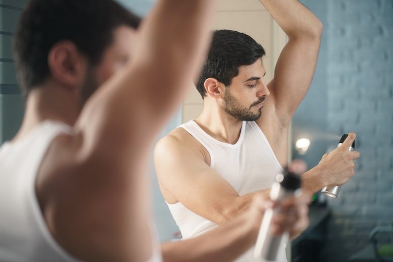 Man spraying deodorant under his arms