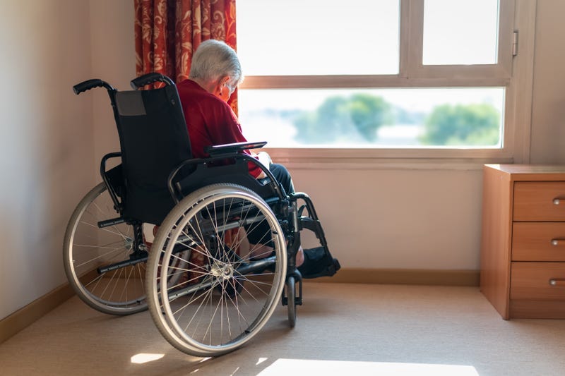 Lonely older woman sitting in a wheelchair in front of a window