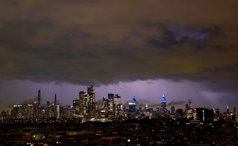 Lightning in Long Island illuminates the sky behind thunderstorm clouds passing over the skyline of midtown Manhattan and the Empire State Building in New York City on Aug. 18, 2024, as seen from Jersey City, New Jersey.