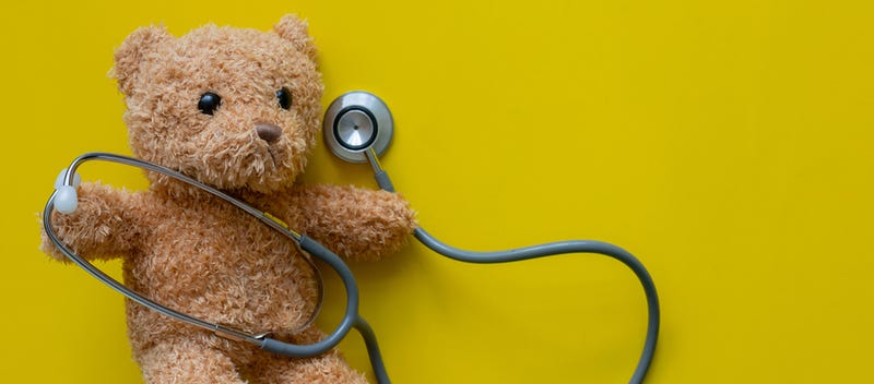 close up teddy bear as paediatrician with stethoscope on yellow color background