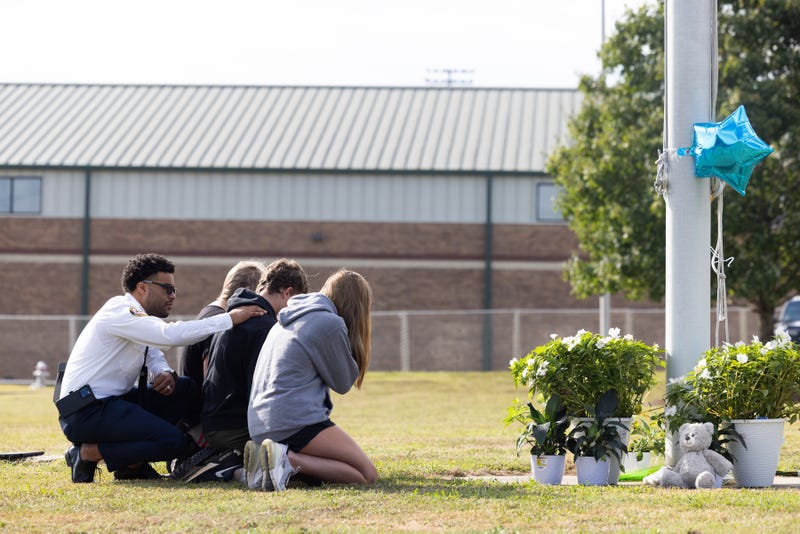 State of Georgia Chaplain Ronald Clark consoles students as they kneel in front of a makeshift memorial at Apalachee High School on Sept. 5, 2024, in Winder, Georgia. Two students and two teachers were shot and killed at the school.