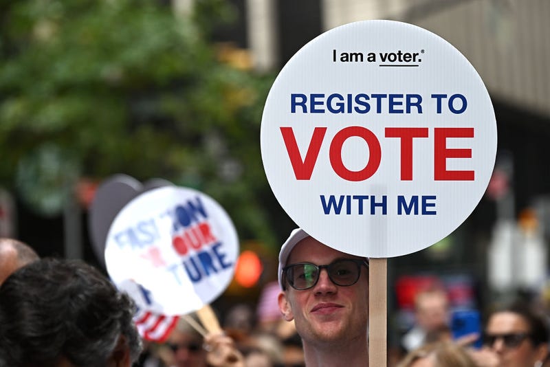 An attendee holds a "Register to Vote" sign at Fashion For Our Future March