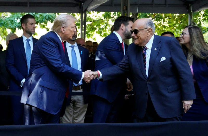 Former US President and Republican presidential candidate Donald Trump (L) shakes hands with former New York City Mayor Rudy Giuliani during the remembrance ceremony