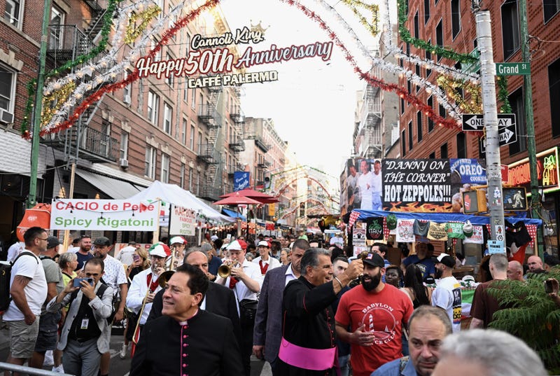 Vendors serving spicy rigatoni and fresh zeppole line the route along Mulberry Street