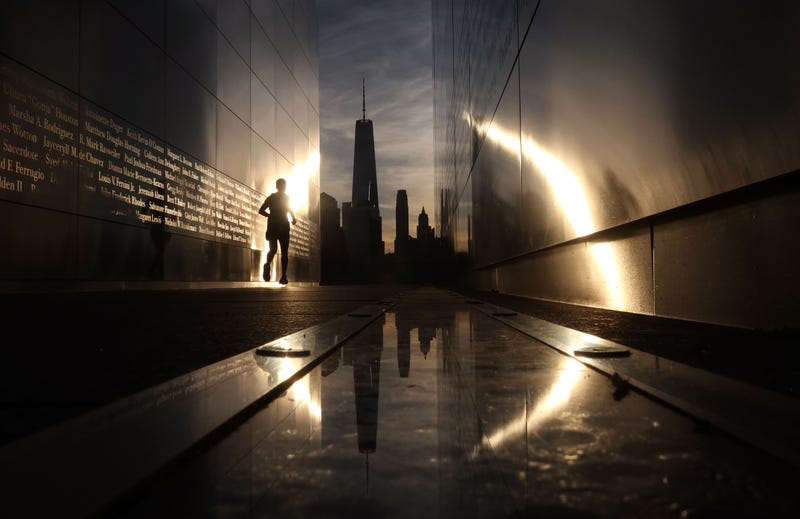 A person runs though the Empty Sky 9/11 memorial as the sun rises behind the skyline of Lower Manhattan on September 11, 2024