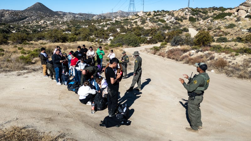 From an aerial view U.S. Border Patrol agents gather a group of Colombian asylum seekers after they crossed over from Mexico on September 22, 2024 near Jacumba Hot Springs, California. Immigrant border crossings remained low months after the Biden Administration's executive order banning most asylum claims at the southern border. The issues of asylum and illegal immigration were a main motivating topic for voters during the U.S. election.