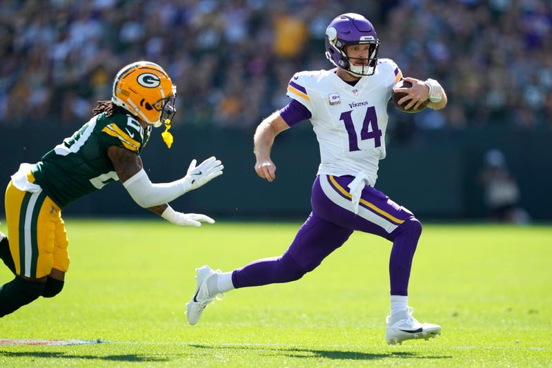 Sam Darnold #14 of the Minnesota Vikings carries the ball past Javon Bullard #20 of the Green Bay Packers during the first half at Lambeau Field on September 29, 2024 in Green Bay, Wisconsin.