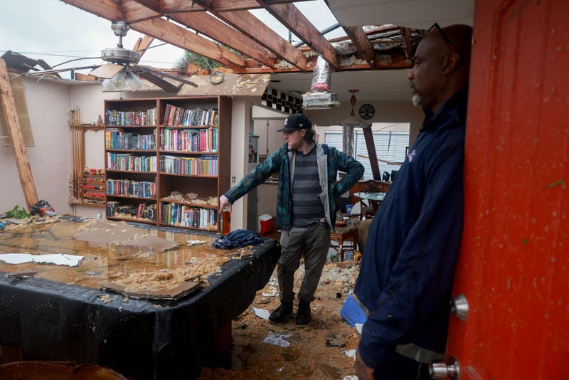 Connor Ferran (L) and his neighbor Leroy Roker survey what is left after what appeared to be a tornado tore the roof off of Ferran's home.