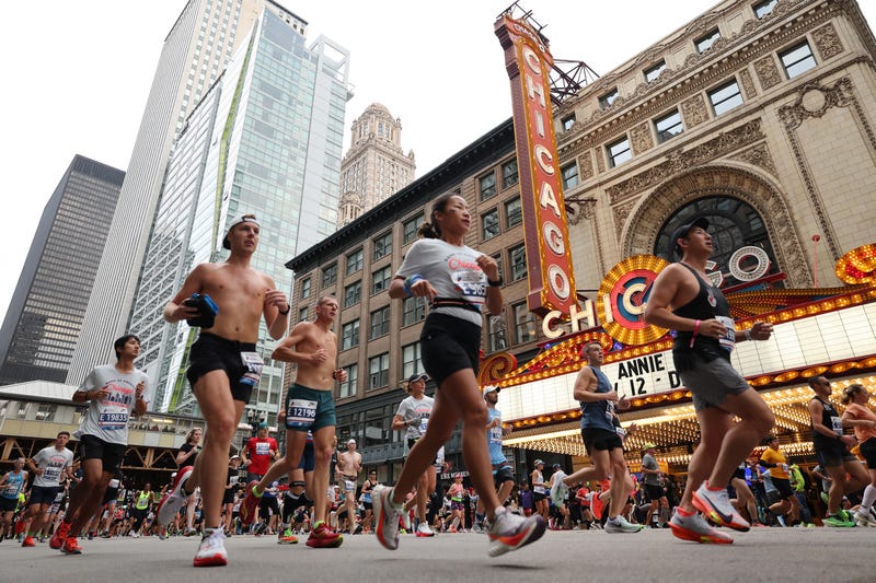 Runners pass the Chicago Theatre
