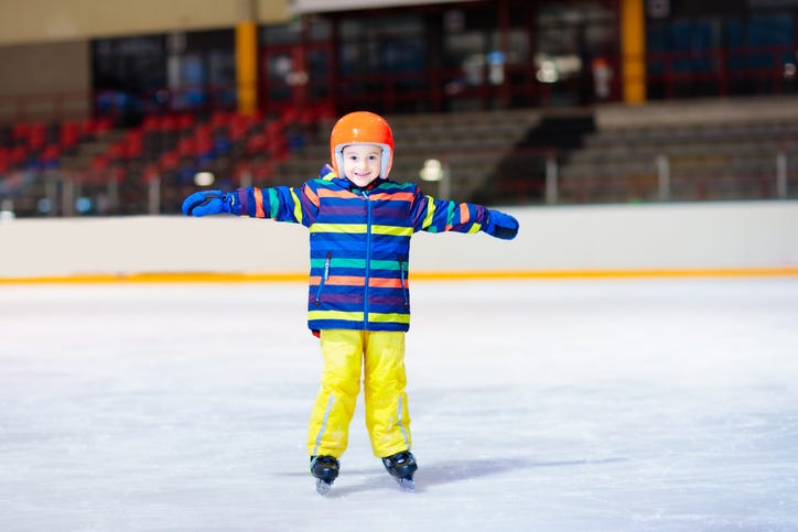 Child skating on indoor ice rink. Kids skate. Active family sport during winter vacation and cold season. Little boy in colorful wear training or learning ice skating. School sport activity and clubs