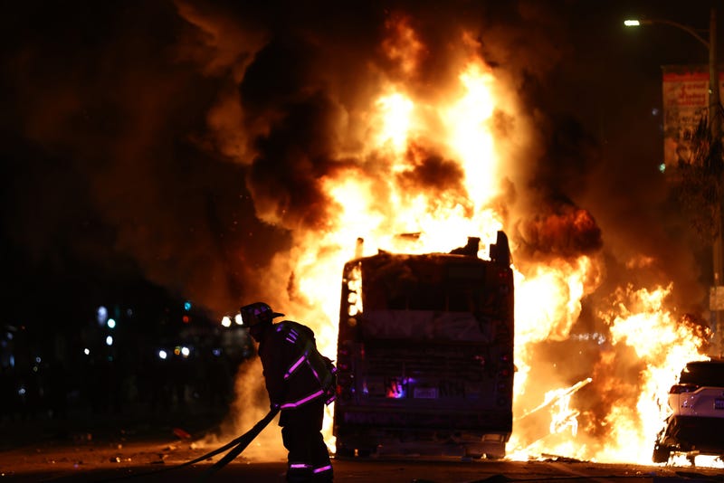 A firefighter works as a Metro bus burns following Dodger fan celebrations in the area which turned unruly, after the Los Angeles Dodgers defeated the New York Yankees in Game 5 to win the World Series, on October 31, 2024 in Los Angeles, California. 