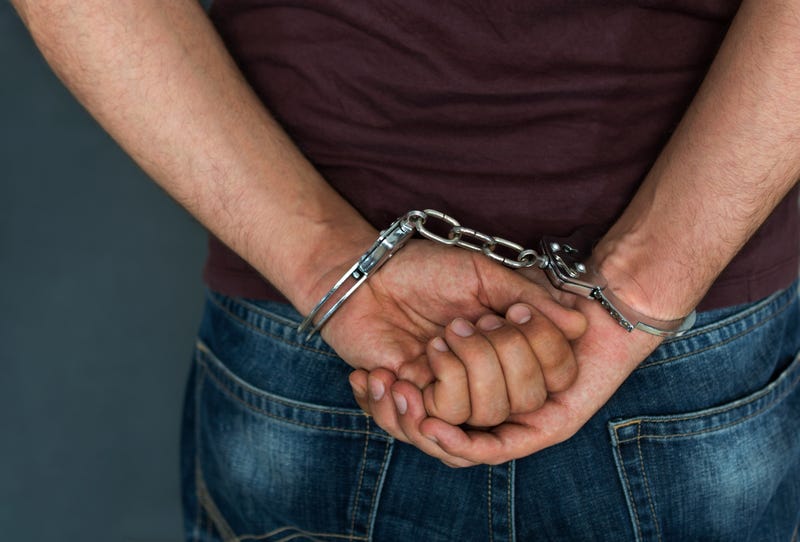 A man's wrists are handcuffed behind his back