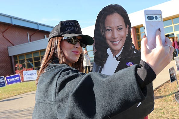 People take pictures with a Democratic nominee Vice President Kamala Harris cutout after voting