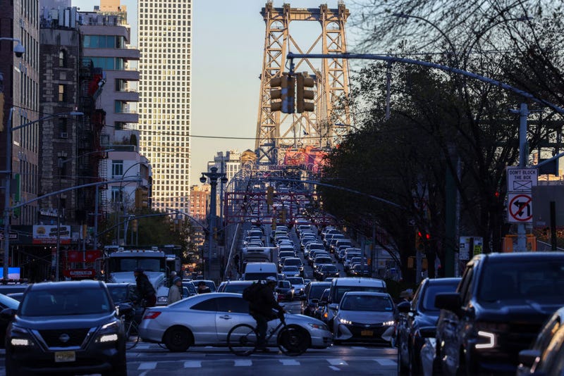 Pedestrians, cyclists and cars move along Delancey Street, with the Williamsburg Bridge in the background, in Manhattan on Nov. 13, 2024.
