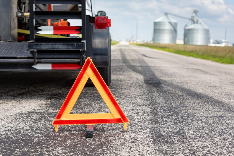 Work trailer on side of road with warning triangle. Emergency roadside assistance, work zone, and towing safety concept. - stock photo