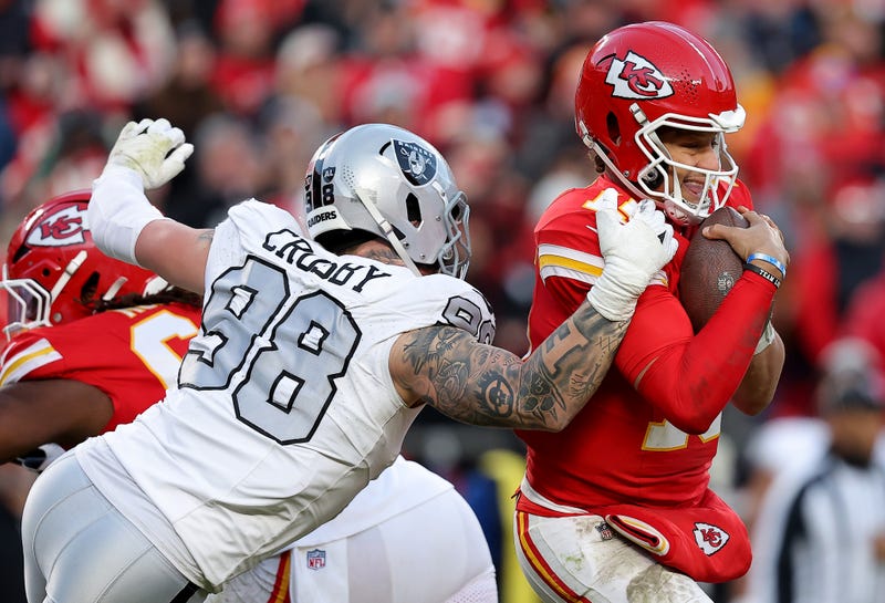 : Patrick Mahomes #15 of the Kansas City Chiefs escapes a sack against Maxx Crosby #98 of the Las Vegas Raiders during the third quarter in the game at GEHA Field at Arrowhead Stadium on November 29, 2024 in Kansas City, Missouri.