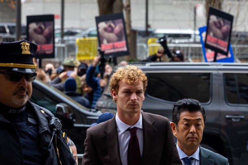 Daniel Penny arrives at the Manhattan Criminal Courthouse on Dec. 9, 2024, as protesters hold up images of him restraining Jordan Neely on a subway train in 2023