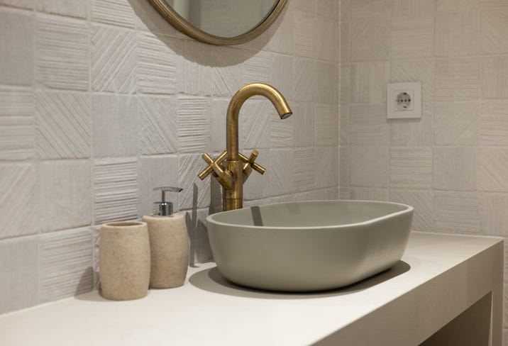 This modern bathroom design showcases a sleek basin along with luxurious gold fixtures for an elegant look