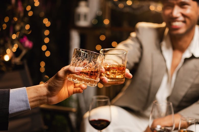 Two men clinking glasses of whiskey