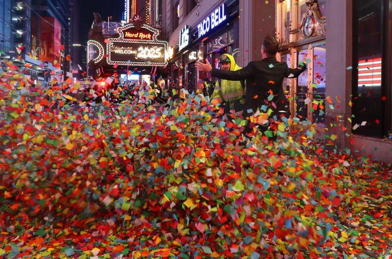 A man stands on a sidewalk filled with confetti as Dept. of Sanitation workers begin the cleanup following New Year's Eve festivities in Times Square on Jan. 1, 2025, in New York City.