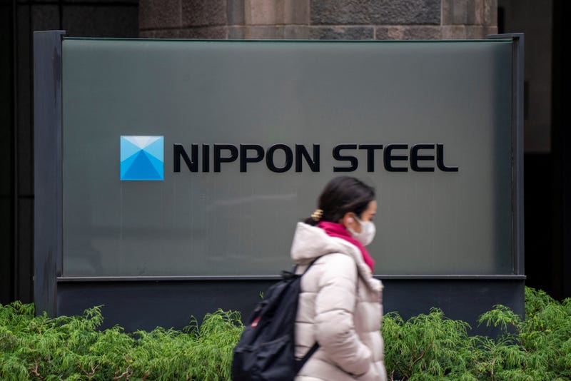 woman walks past the logo of Japan's largest steel manufacturer Nippon Steel corporation