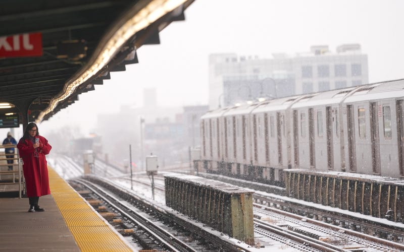 A woman waits at a subway station during snowfall on January 6, 2025