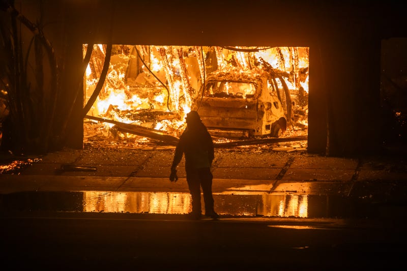 LOS ANGELES, CALIFORNIA - JANUARY 8: A firefighter watches the flames from the Palisades Fire burning homes on the Pacific Coast Highway amid a powerful windstorm on January 8, 2025 in Los Angeles, California. The fast-moving wildfire has grown to more than 2900-acres and is threatening homes in the coastal neighborhood amid intense Santa Ana Winds and dry conditions in Southern California.